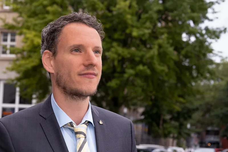 Business-Portrait im Freien: Mann im grauen Anzug mit gestreifter Krawatte vor unscharfem Stadtgrün