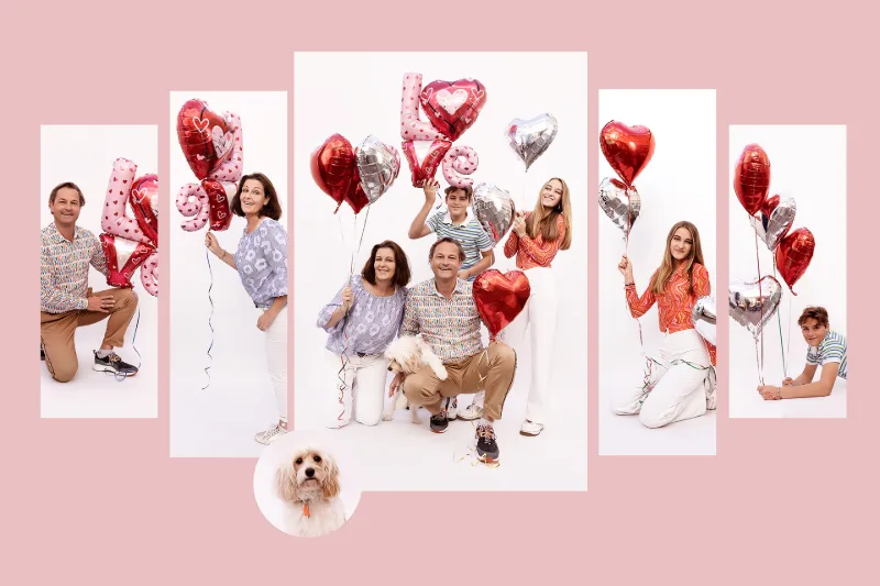 Familie mit Herzluftballons, die das Wort LOVE bilden, vor rosa Hintergrund, mit dem Familienhund