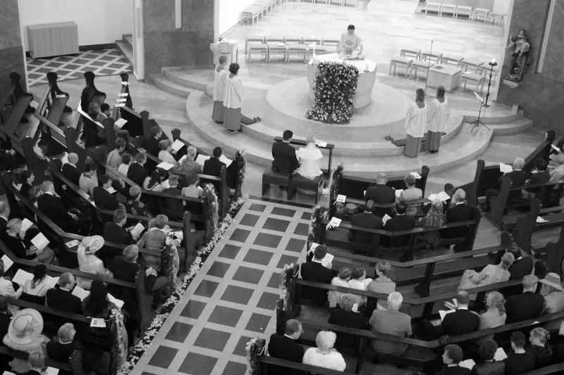 Übersichts-Aufnahme einer Trauung in einer modernen Kirche, von der Empore aus – Gemeinde in den Bänken, Brautpaar vor dem Altar