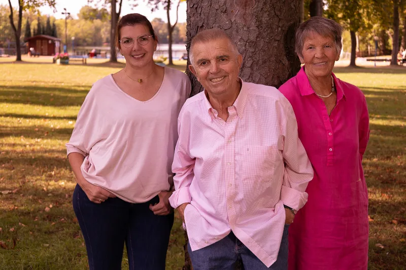 Familien-Porträt im Park: zwei Frauen und ein Mann in Rosa- und Pinktönen vor einem Baum am See in Duisburg